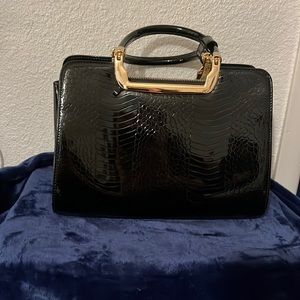 An elegant black alligator print purse with gold accent side zippered pocket